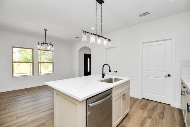 kitchen with light stone countertops, sink, a center island with sink, dishwasher, and light hardwood / wood-style floors