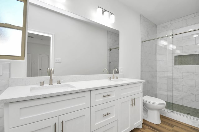 bathroom with hardwood / wood-style flooring, vanity, toilet, and a shower with shower door