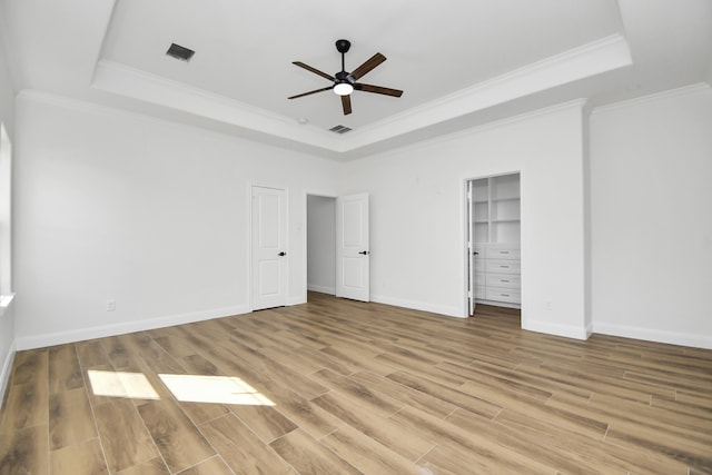 unfurnished bedroom featuring a tray ceiling, light hardwood / wood-style flooring, and ceiling fan