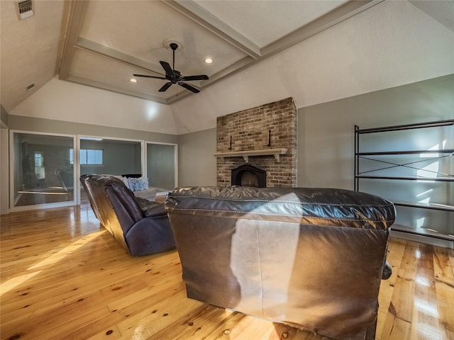 living room with vaulted ceiling with beams, light hardwood / wood-style floors, a brick fireplace, and ceiling fan