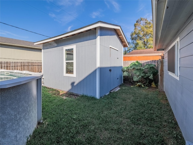 view of home's exterior with a pool, a yard, and a storage shed