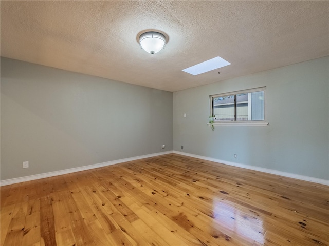 unfurnished room with wood-type flooring, a textured ceiling, and a skylight