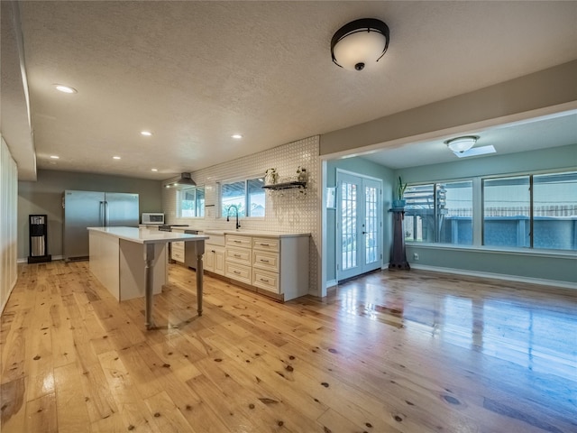 kitchen with stainless steel fridge, french doors, a breakfast bar, a center island, and light hardwood / wood-style floors