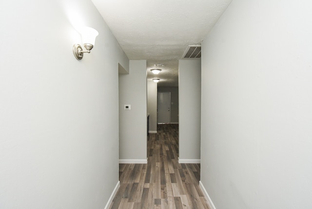 hallway with dark wood-type flooring and a textured ceiling