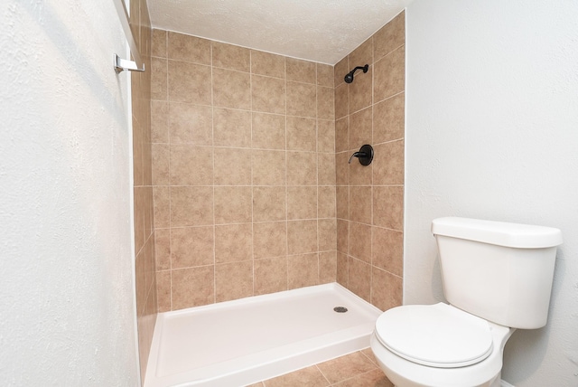 bathroom with tiled shower, tile patterned floors, a textured ceiling, and toilet