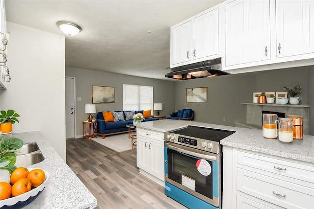 kitchen featuring white cabinetry, light stone counters, stainless steel electric range, and light wood-type flooring