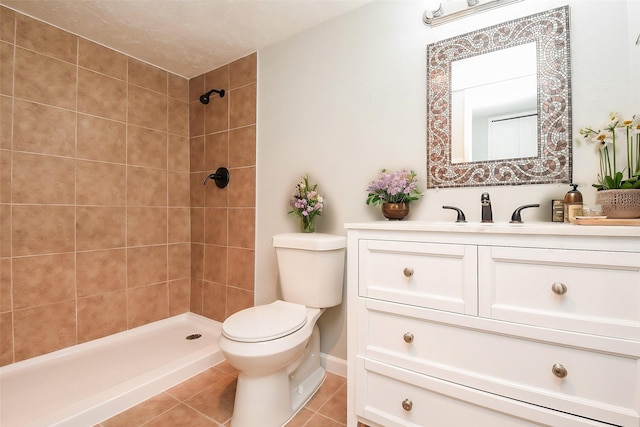 bathroom featuring tile patterned floors, toilet, vanity, and a tile shower