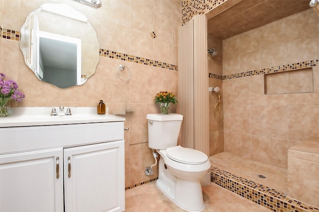 bathroom featuring tiled shower, toilet, tile walls, vanity, and tile patterned flooring