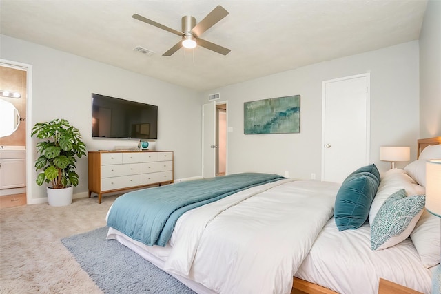 carpeted bedroom with ceiling fan and ensuite bath