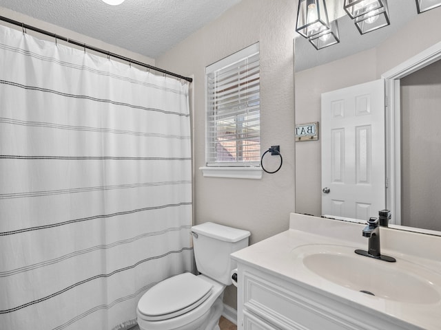 bathroom with vanity, a textured ceiling, toilet, and walk in shower