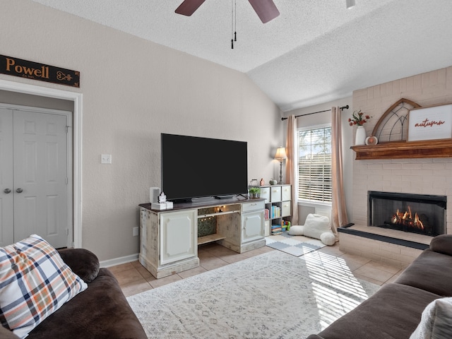 living room featuring lofted ceiling, a brick fireplace, ceiling fan, light tile patterned floors, and a textured ceiling