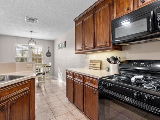 kitchen with a textured ceiling, black appliances, light tile patterned floors, a chandelier, and hanging light fixtures