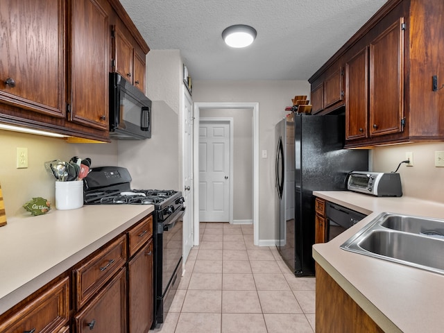 kitchen featuring sink, light tile patterned floors, a textured ceiling, and black appliances