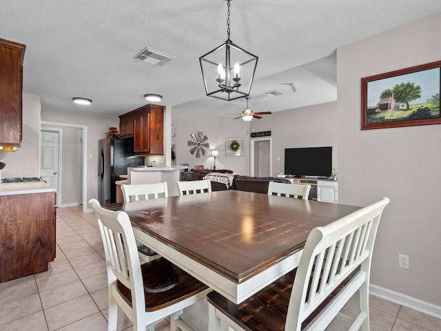 tiled dining space featuring ceiling fan with notable chandelier and a textured ceiling