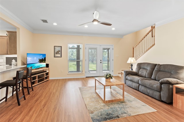 living room featuring crown molding, light hardwood / wood-style flooring, ceiling fan, and french doors