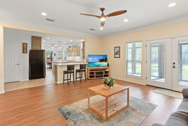 living room with french doors, light hardwood / wood-style floors, ceiling fan, and crown molding