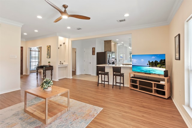 living room featuring crown molding, ceiling fan, and light hardwood / wood-style floors