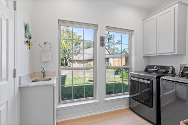 laundry area with washer and clothes dryer, sink, cabinets, and plenty of natural light