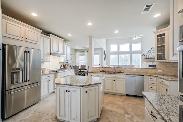 kitchen with ceiling fan, sink, kitchen peninsula, a kitchen island, and appliances with stainless steel finishes