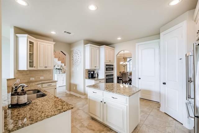 kitchen featuring light stone countertops, tasteful backsplash, stainless steel appliances, sink, and a center island