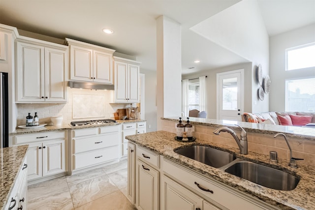 kitchen with light stone countertops, appliances with stainless steel finishes, tasteful backsplash, and sink