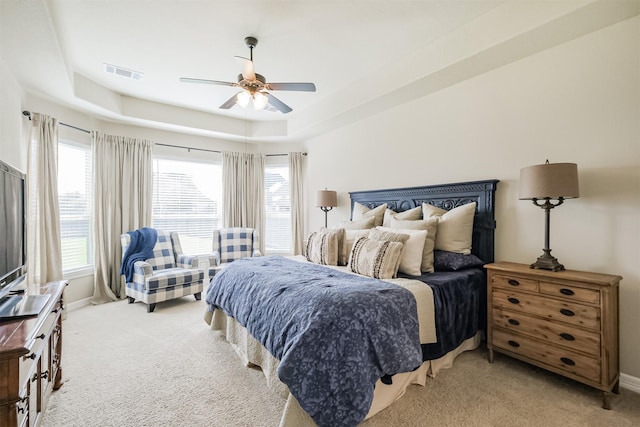 carpeted bedroom featuring ceiling fan and a raised ceiling