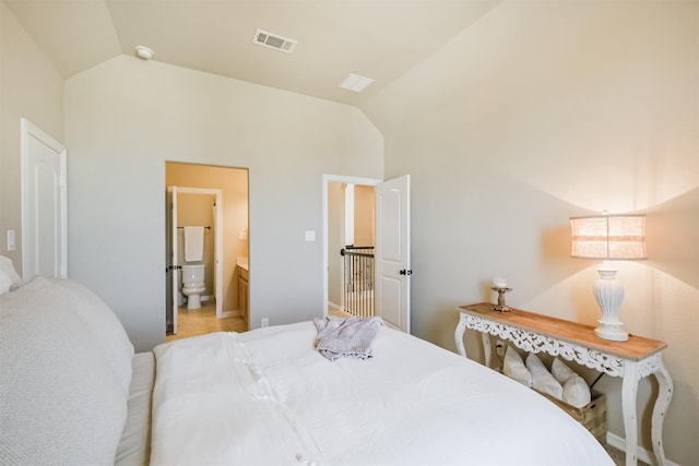 bedroom featuring ensuite bathroom and lofted ceiling