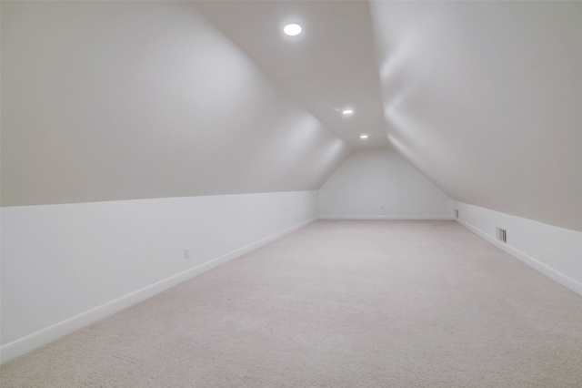 additional living space with light carpet and vaulted ceiling