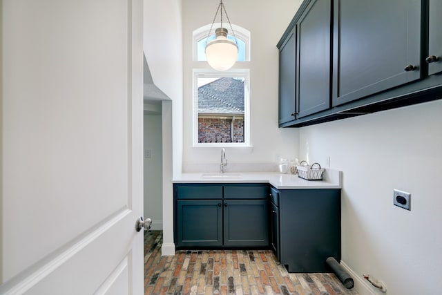 clothes washing area with electric dryer hookup, cabinets, light wood-type flooring, and sink