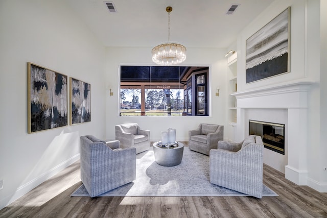 living room with built in shelves, a notable chandelier, and hardwood / wood-style flooring