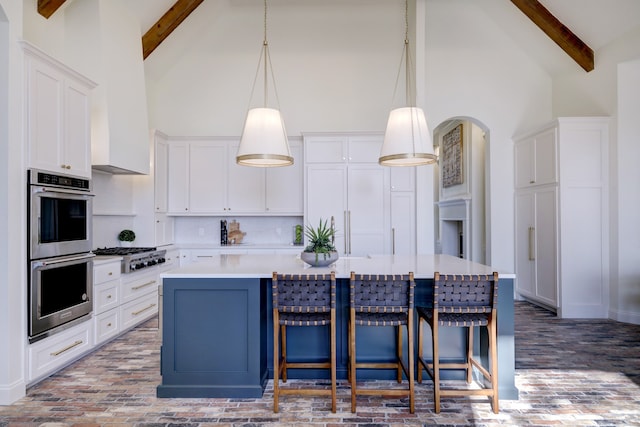 kitchen featuring white cabinets, decorative light fixtures, stainless steel appliances, and beamed ceiling