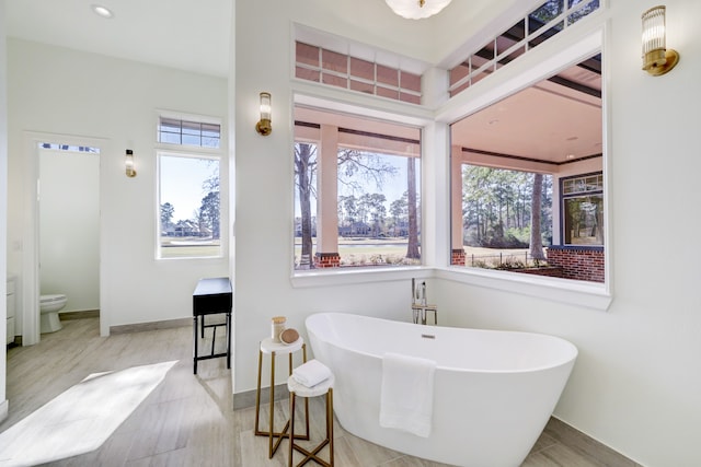 bathroom featuring a bathtub, hardwood / wood-style floors, plenty of natural light, and toilet