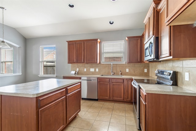 kitchen with sink, vaulted ceiling, tasteful backsplash, decorative light fixtures, and stainless steel appliances