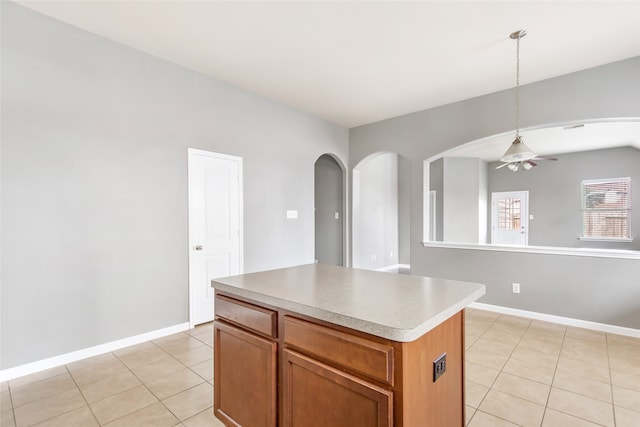 kitchen featuring ceiling fan, a center island, light tile patterned floors, and hanging light fixtures