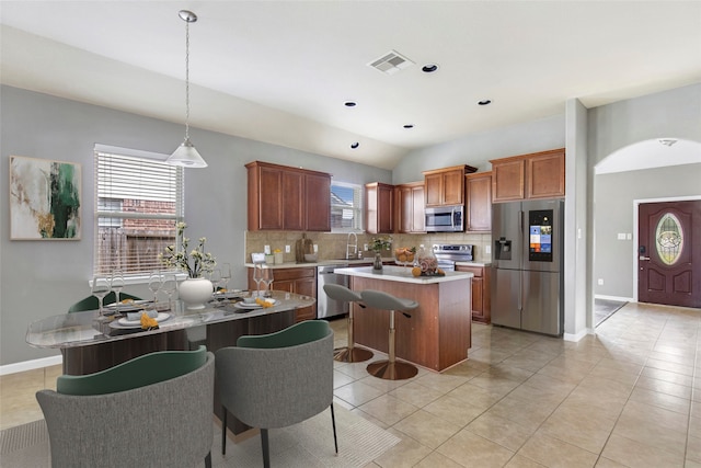 kitchen with backsplash, a kitchen island, hanging light fixtures, and appliances with stainless steel finishes