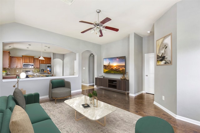 living room featuring ceiling fan, sink, dark wood-type flooring, and vaulted ceiling