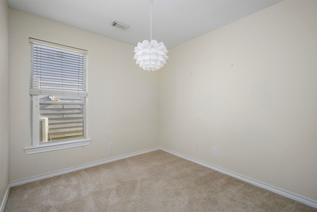 carpeted spare room with a notable chandelier