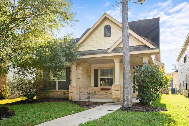 craftsman-style house featuring cooling unit, covered porch, and a front yard