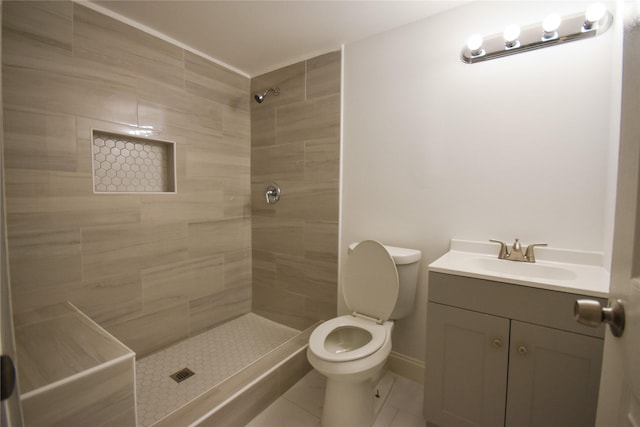 bathroom with tile patterned flooring, vanity, toilet, and tiled shower