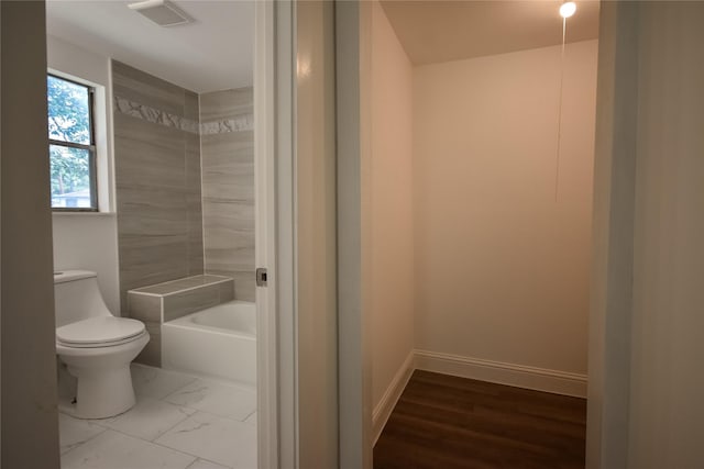 bathroom featuring a tub, hardwood / wood-style flooring, and toilet