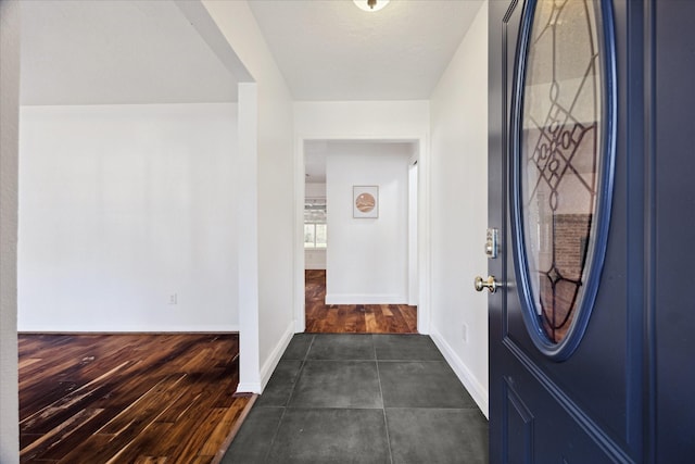 foyer entrance with dark wood-style floors and baseboards