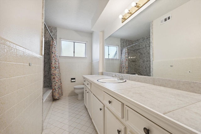 full bath with visible vents, toilet, tile patterned floors, vanity, and tile walls