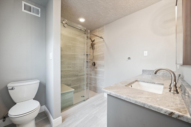 full bath featuring a stall shower, visible vents, toilet, a textured ceiling, and vanity