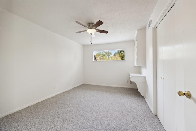 unfurnished bedroom with ceiling fan, a textured ceiling, light carpet, baseboards, and a closet