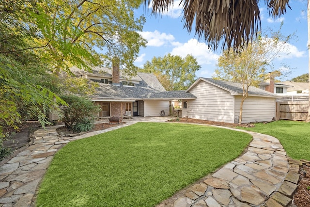 back of house featuring a patio, a chimney, fence, a yard, and brick siding