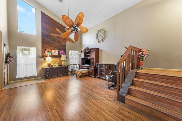 living room featuring hardwood / wood-style floors, a towering ceiling, and ceiling fan