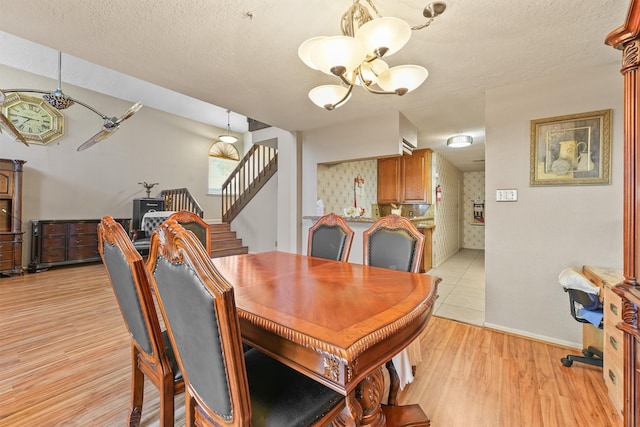 dining space featuring a notable chandelier, a textured ceiling, and light hardwood / wood-style flooring