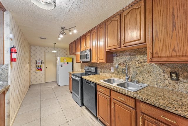 kitchen featuring sink, stainless steel appliances, light stone counters, a textured ceiling, and light tile patterned floors