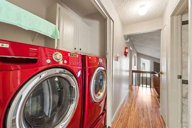 clothes washing area with light hardwood / wood-style flooring, a textured ceiling, and independent washer and dryer