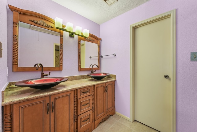 bathroom with vanity, a textured ceiling, and tile patterned floors